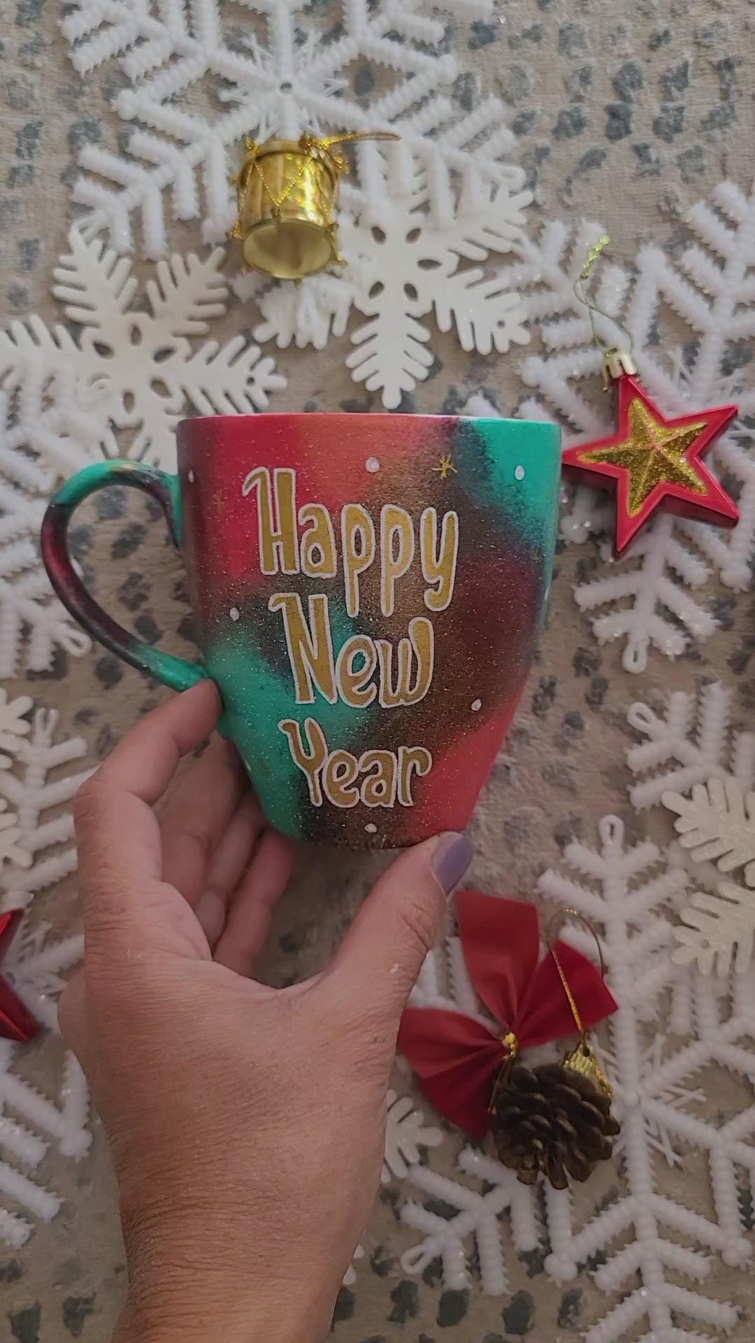 A Christmas hand painted mug with the words "Happy new year" written in gold and the name Dina on the other side