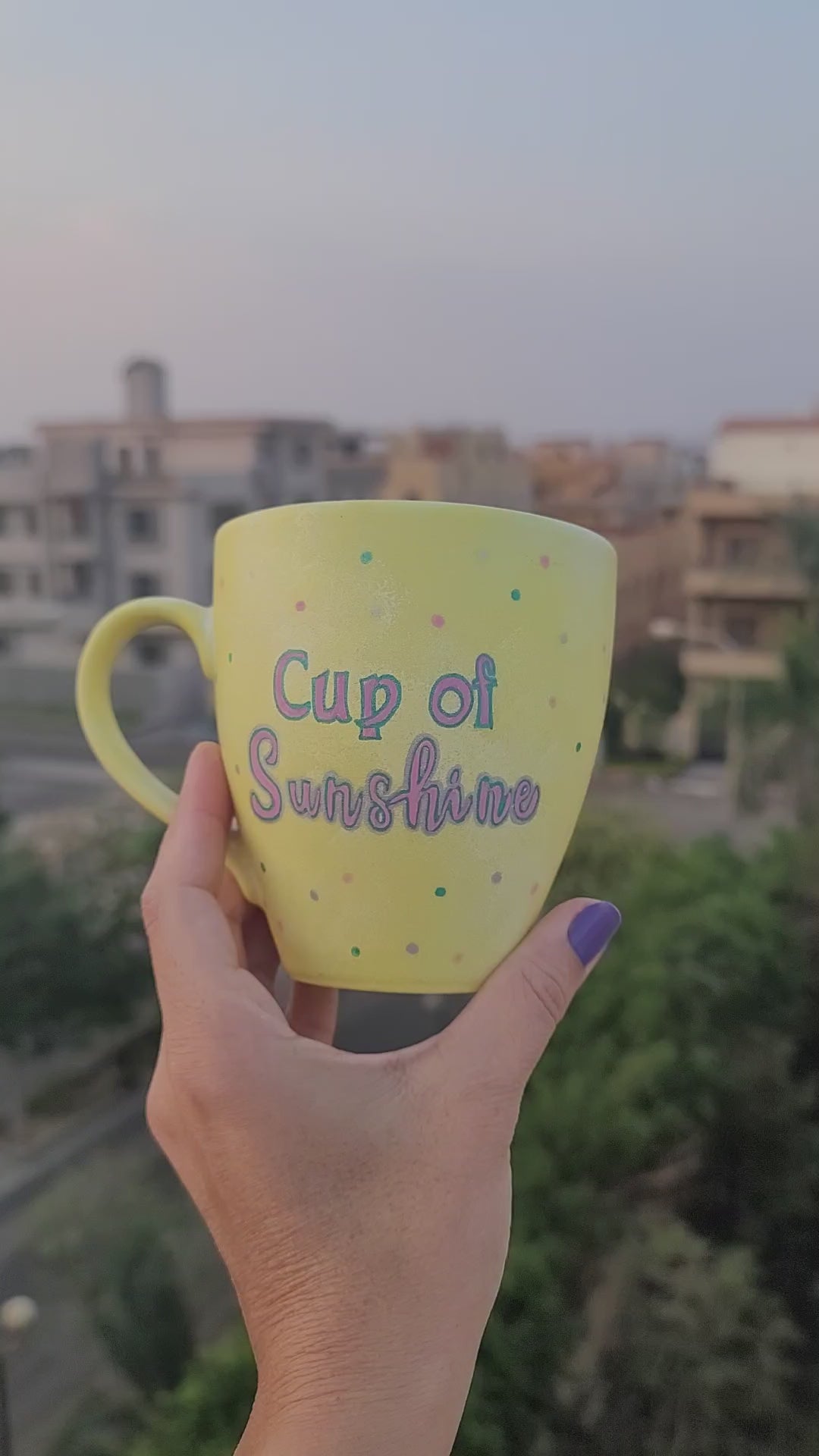 A Pastel yellow hand painted mug with the words "Cup of Sunshine" and on the other side a sun painted in pink and turquoise