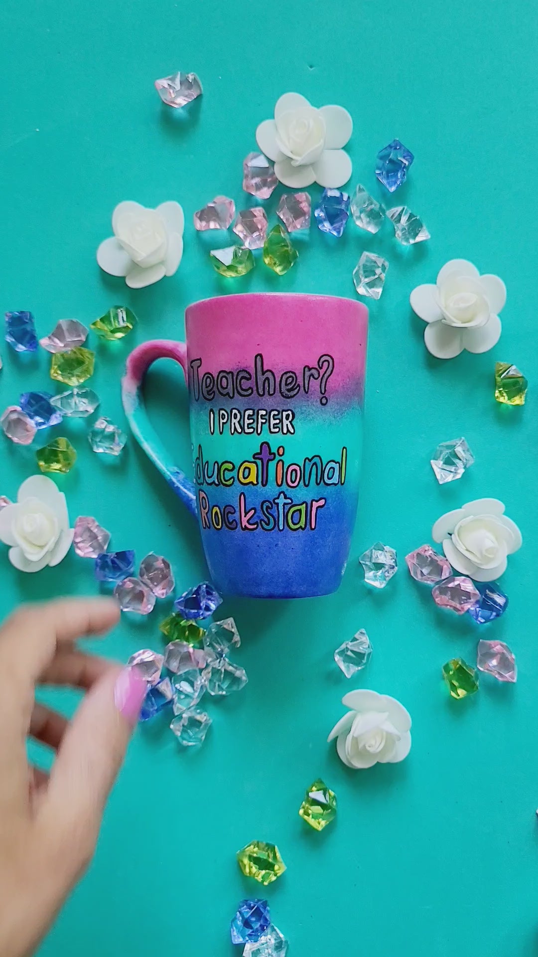 A Gradient hand painted mug (Pink Green and ultramarine) with the sentence "Teacher? I prefer Educational Rockstar" and the name "Shereen" on the other side