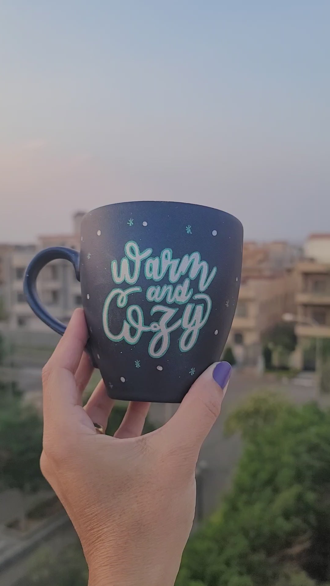 A Shimmery blue hand painted mug with the words "Warm and Cozy " in silver and on the other side a silver snowflake