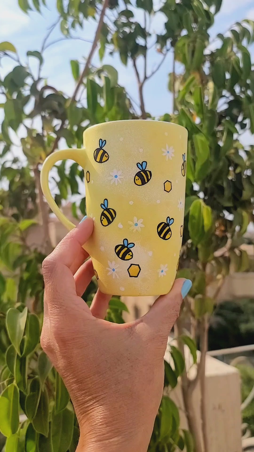 A Pastel yellow Hand painted mug with bees , white flowers and honey combs scattered all over