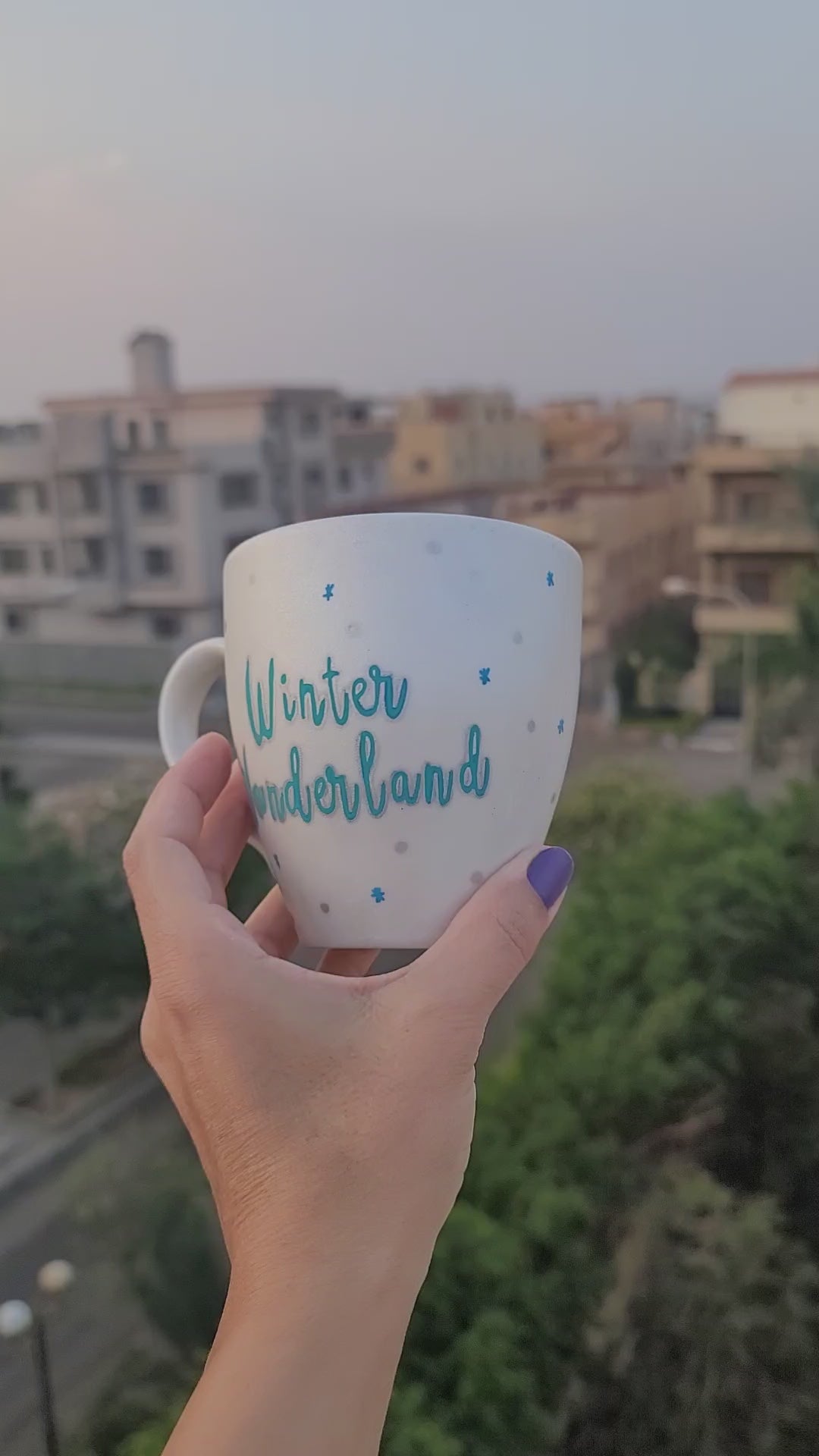 A Pearl White Hand painted mug with the words "Winter Wonderland" on turquoise and on the other side a snowflake