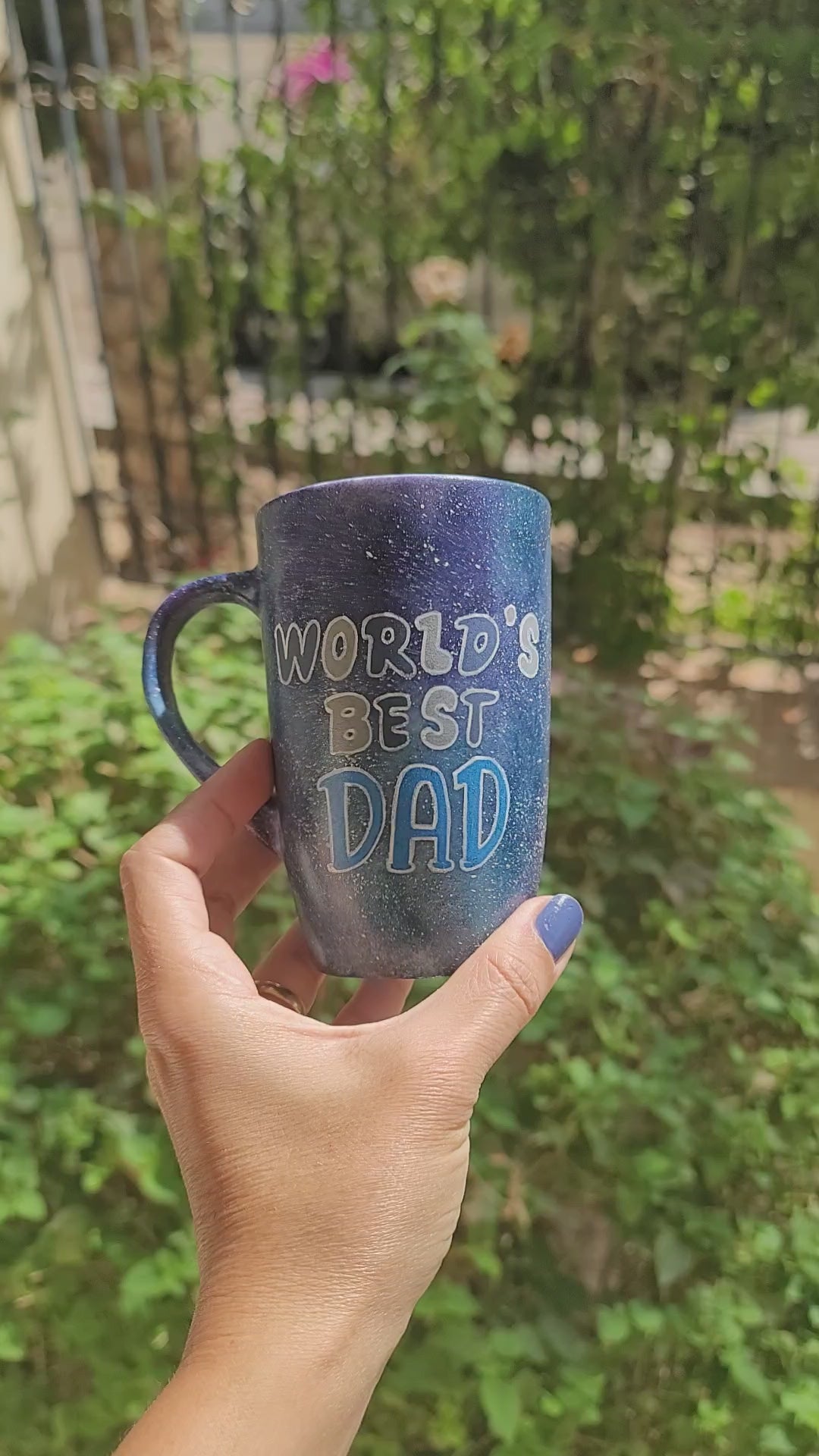 A black galaxy hand painted mug with the sentence "Worlds Best dad" and the other side has the name "Amore" with a crown on the letter A