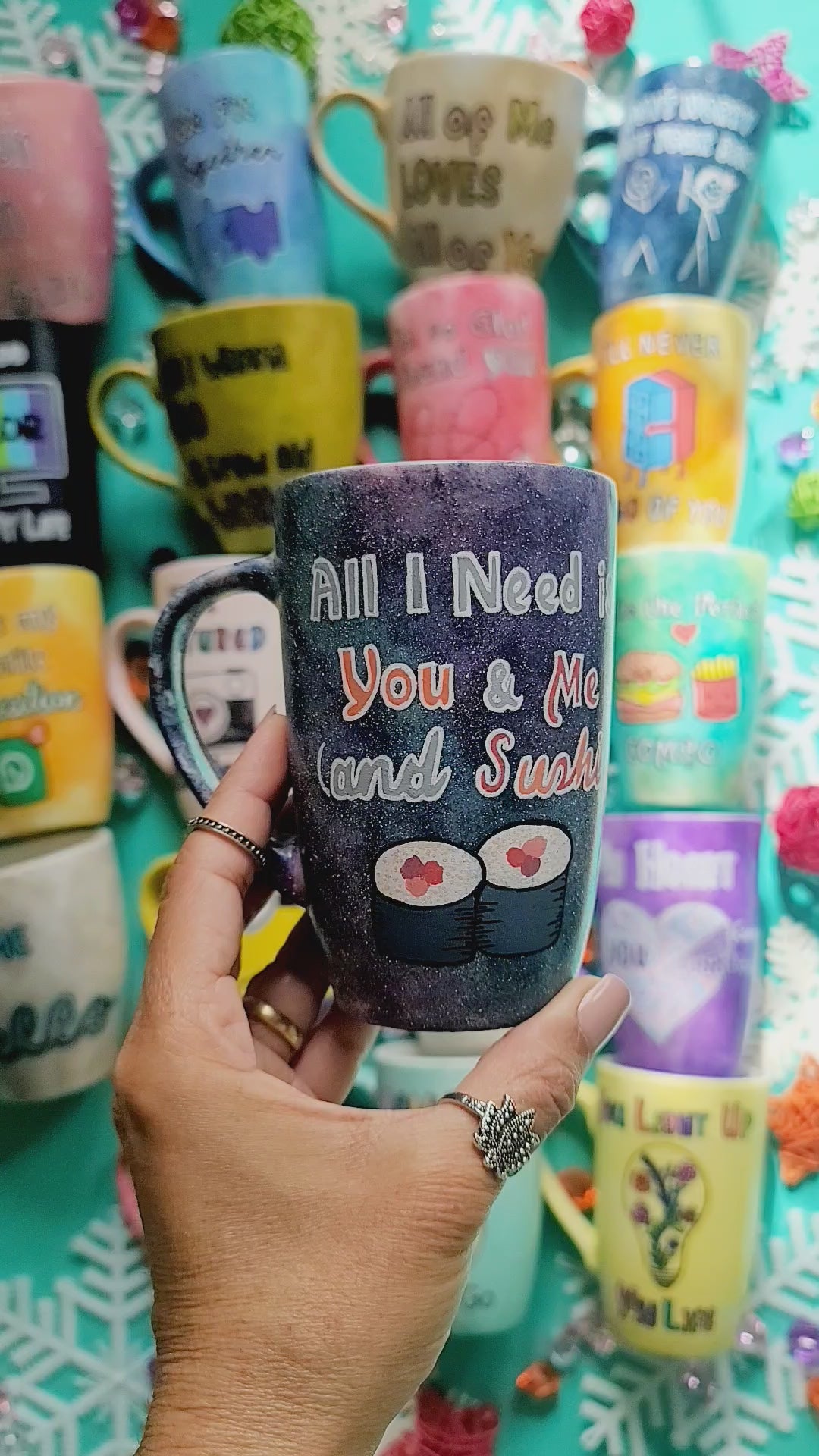 A Hand Painted Black Galaxy Mug with the sentence "All I need is You and ME and Sushi" and 2 sushi rolls drawn below it and on the other side the name "Tamer"