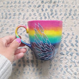 A gradient hand painted mug(rainbow colors in the top half and black galaxy in the bottom