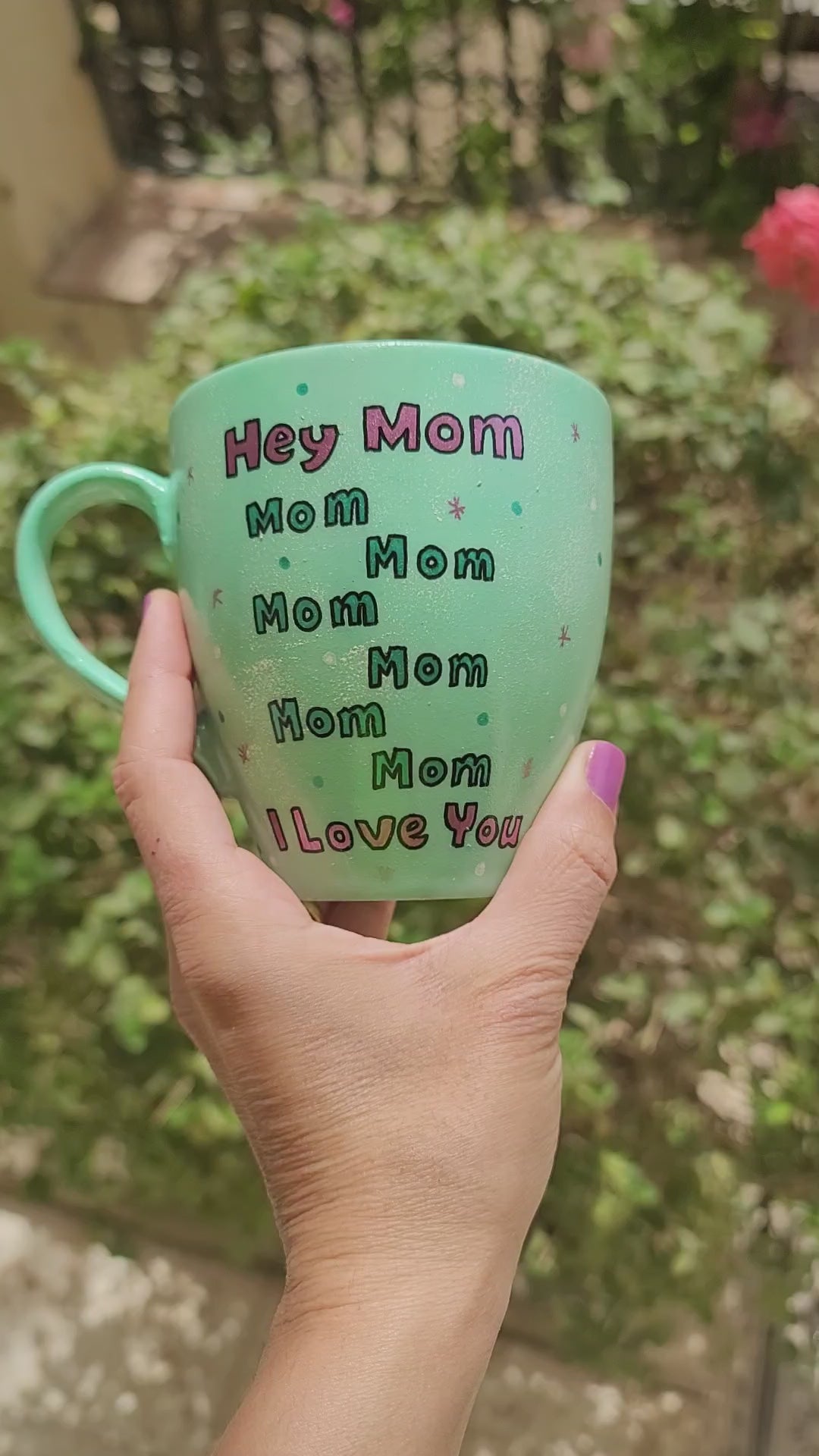 A mint Colored mug with the sentence "Hey mom mom mom mom mom mom I love you" with white and green dots and pink stars scattered all over and on the other side the name "Roby"