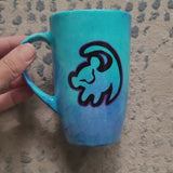 A Blue Hand painted mug with the an outline of baby lion in black and the other side has the sentence 