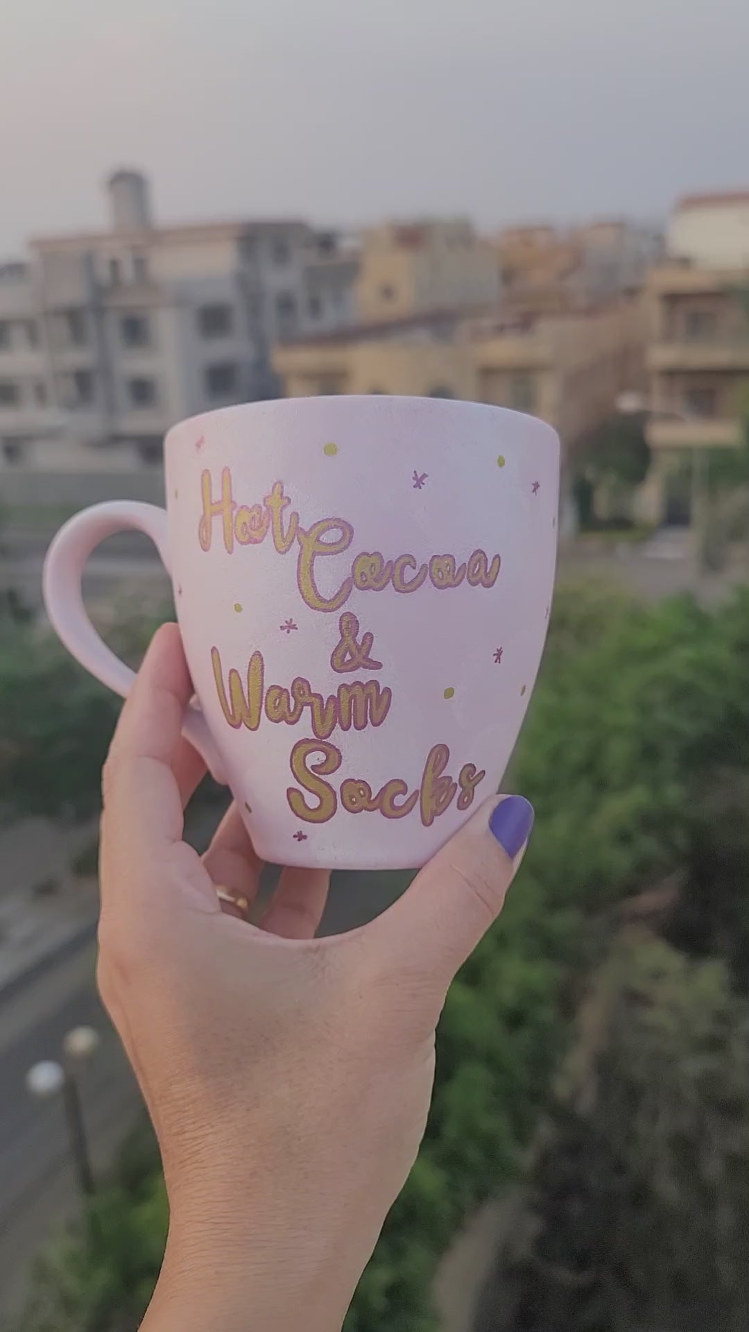 A Hand painted Baby Pink mug with the sentence "Hot Cocoa and warm socks" in gold and the other side has a snowflake