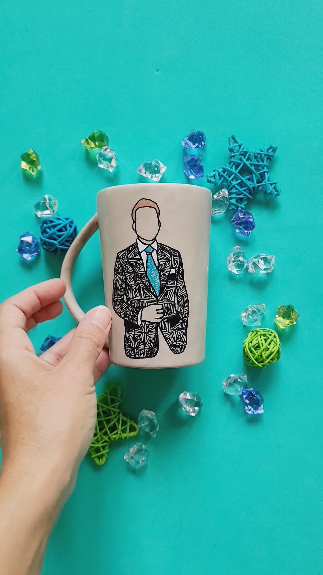 A taupe hand painted mug with a silhouette of a man in a suit filled with patterns and the other side has the words "la petit CEO"