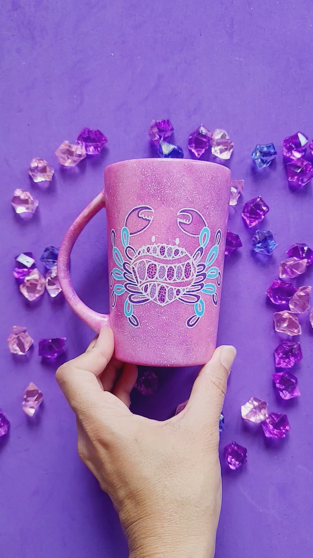 A video showing a hand-painted pink galaxy mug having a cancer sign drawn on one side and the words "mama" on the other