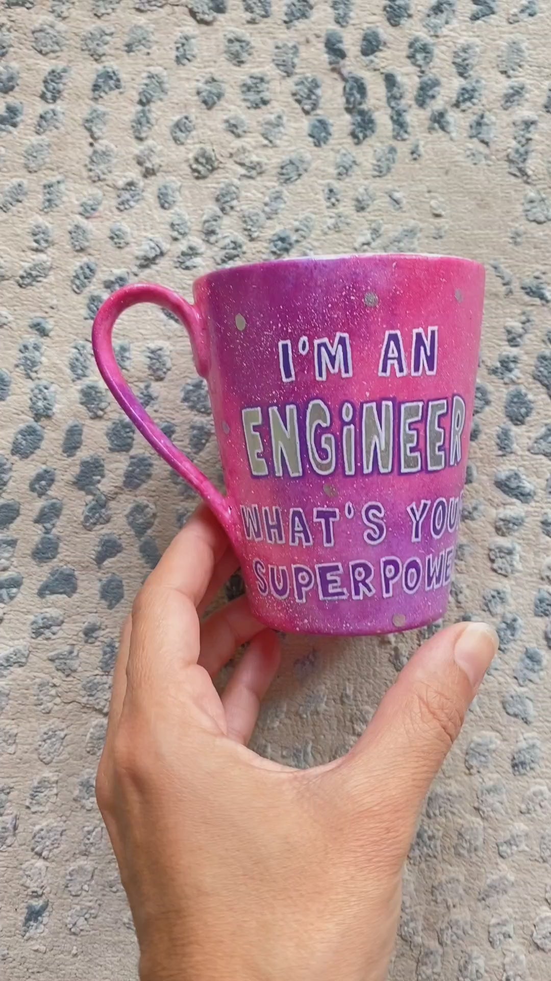 A Pink galaxy hand painted mug with the sentence "I'm and Engineer what your superpower" and the other side has the name Romi