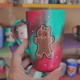 A Christmas hand painted mug with aa gingerbread cookie girl on it with a bow and the other side has the name 