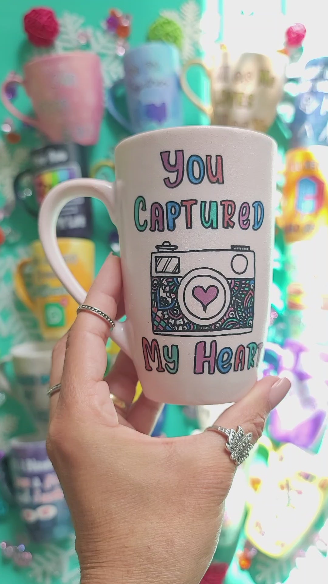 A pale pink mug with the words "you captured" and then below it a camera painted with a heart in the camera center, then below it the words "my heart", then on the other side the name "Yasmine"