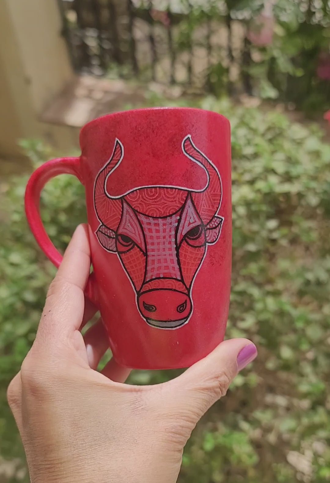 A video Showing a  hand-painted red black mug with Taurus sign on one side and the name "hend" on the other