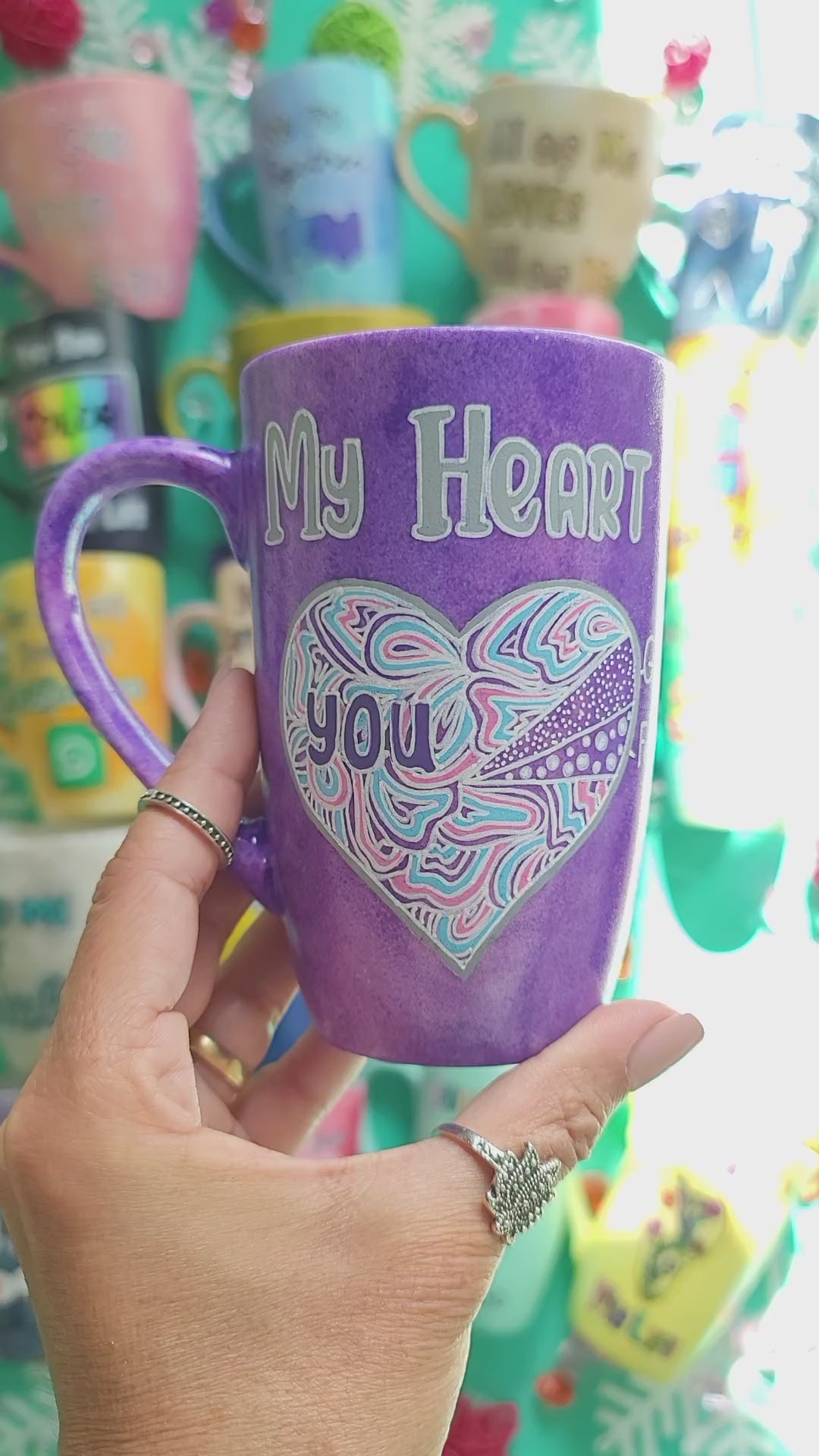 A Hand-Painted Purple galaxy mug with the words "My heart" and a large heart painted divided into a pie chart with a small part"gaming" and another small part"food" and most of the heart written inside it you. and the other side the name "Mai"