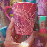 A hand-painted pink galaxy mug with a quarter mandala drawn in the corner and the word together on the other side in silver and white outline