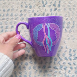 A video showing a purple hand-painted mug with a gemini sign on one side and the word 