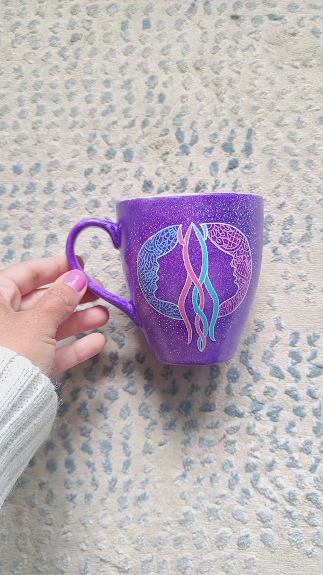 A video showing a purple hand-painted mug with a gemini sign on one side and the word "Gemini" on the other