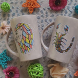 2 hand-painted taupe mugs, one with the scoprio sign on one side and the words 