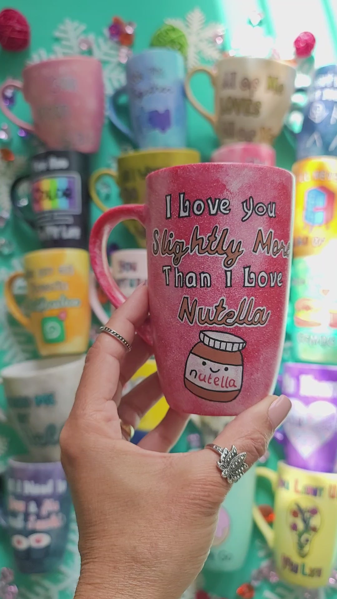 A red galaxy hand painted mug with the sentence "I love you slightly more than I love Nutella"and a small Nutella jar Painted with a smiley face. and the name "Laila" on the other side