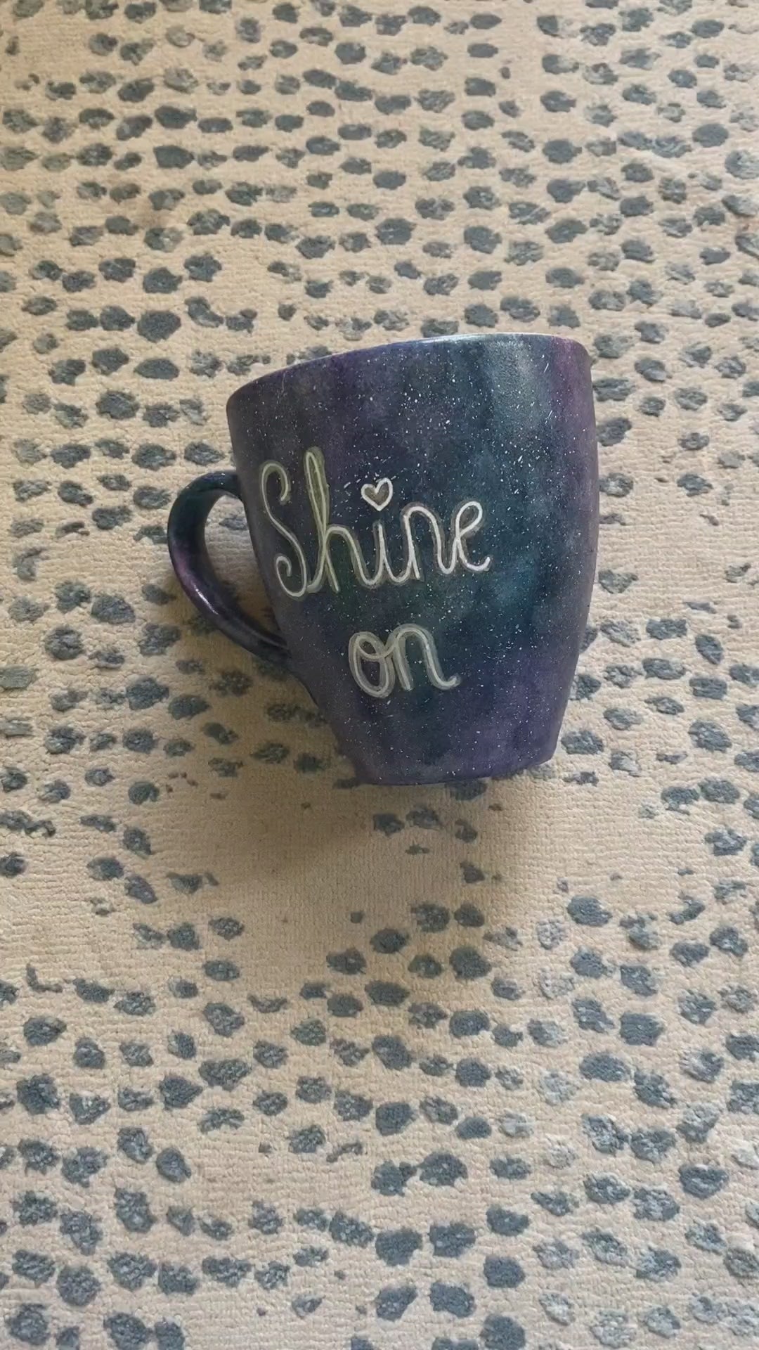 A Black galaxy hand painted mug with the words "Shine on" and the name "Nour" on the other side