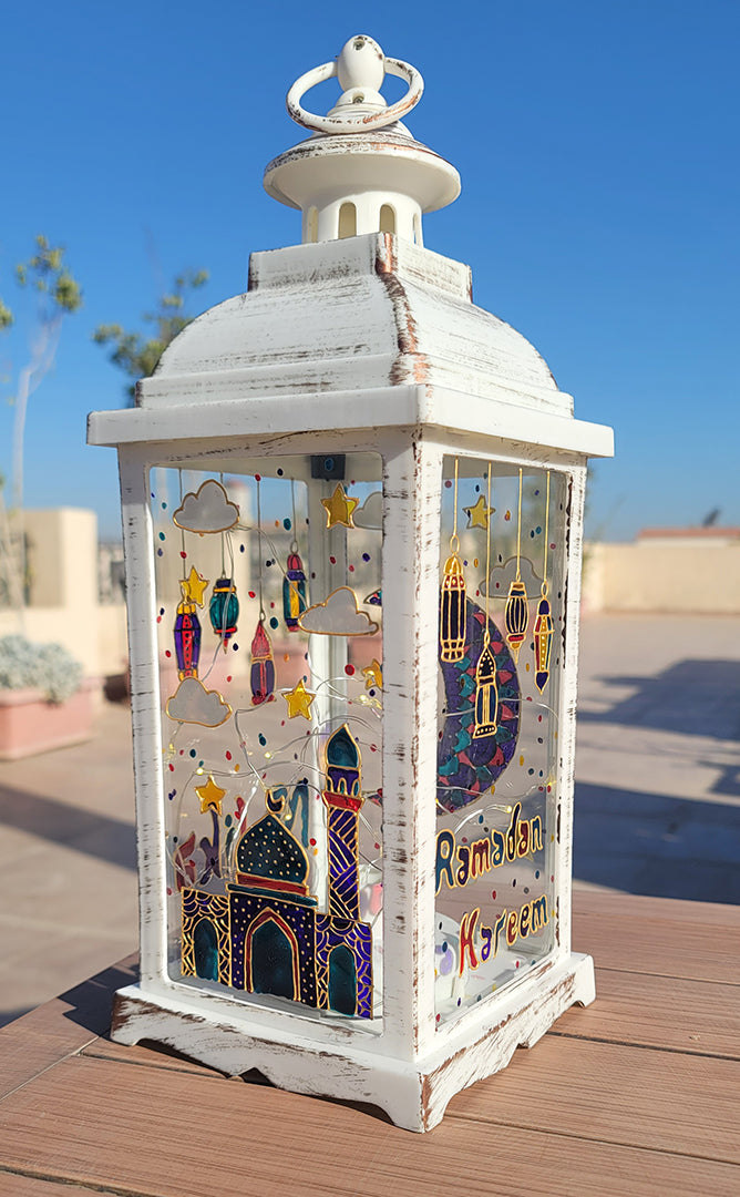 A White vintage lantern with a ramadan design dawn on it with gold relief and the name malika