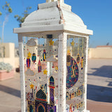 A White vintage lantern with a ramadan design dawn on it with gold relief and the name malika