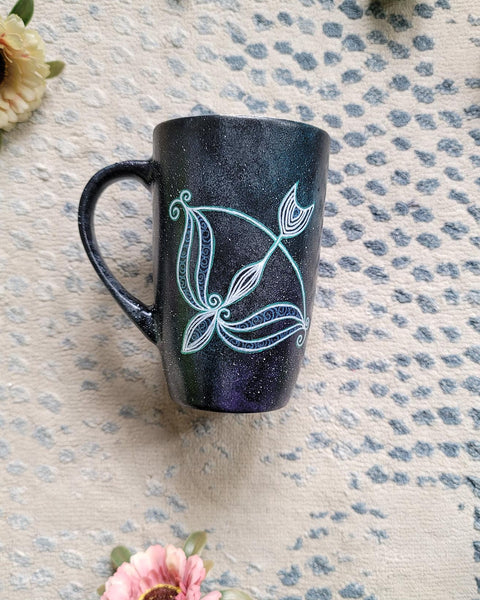 a hand-painted black galaxy mug with a Sagittarius sign