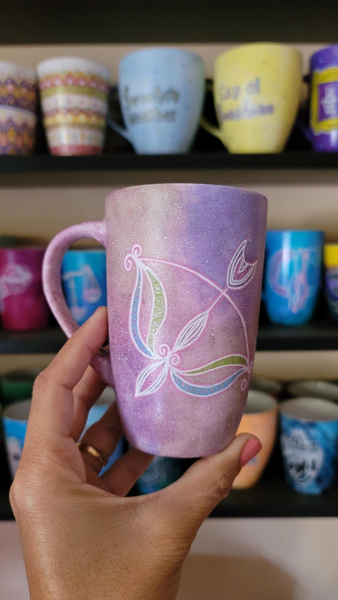 a hand-painted pastel pink galaxy mug with a Sagittarius sign