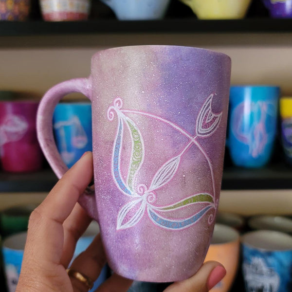 a hand-painted pastel pink galaxy mug with a Sagittarius sign