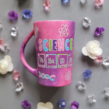 A Pink Galaxy Hand painted mug with the word Science on it and under it the word teacher written in the form of periodic table elements. with science items scattered all over