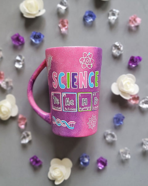 A Pink Galaxy Hand painted mug with the word Science on it and under it the word teacher written in the form of periodic table elements. with science items scattered all over