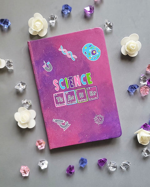 A Pink Galaxy Hand painted notebook with the word Science on it and under it the word teacher written in the form of periodic table elements. with science items scattered all over