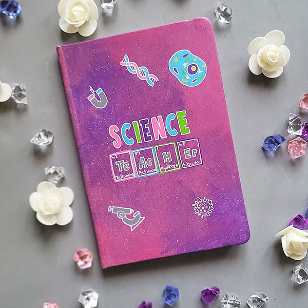 A Pink Galaxy Hand painted notebook with the word Science on it and under it the word teacher written in the form of periodic table elements. with science items scattered all over