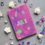 A Pink Galaxy hand painted Notebook with the name Julie written in the center and science items scattered al over 