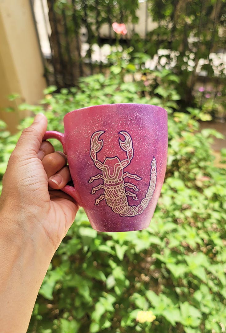 A Pink Galaxy Hand painted Mug With a Scorpio Design on it in white and outlines with purple