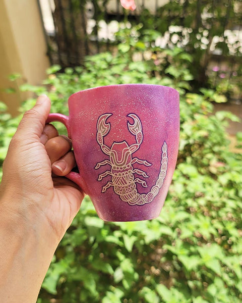 A Pink Galaxy Hand painted Mug With a Scorpio Design on it in white and outlines with purple