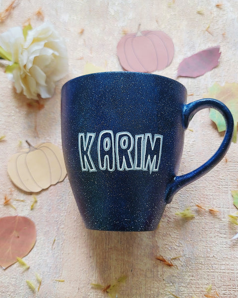 A bLuish Galaxy hand painted mug with the name "karim" written in white