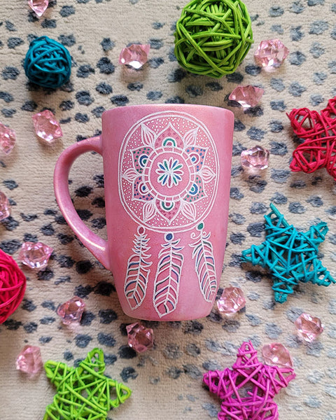 A Shimmery Pink hand painted mug with a dreamcatcher in white and colored in with (pink, blue and teal))