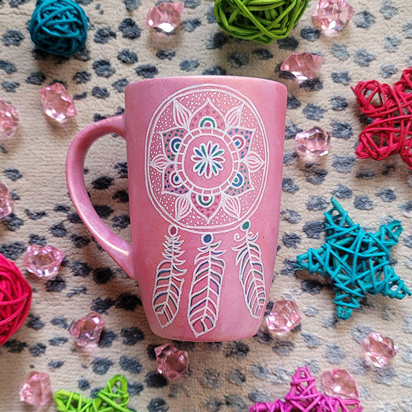 A Shimmery Pink hand painted mug with a dreamcatcher in white and colored in with (pink, blue and teal))