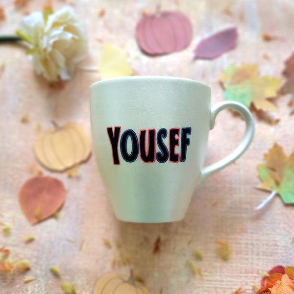 An Ivory hand painted mug with the name "yousef"