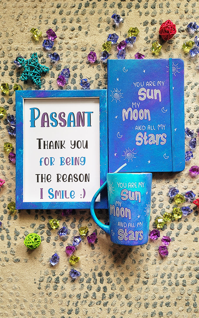 A Blue Galaxy Hand painted mug, notebook and wooden frame with the sentence "you are my Sun, My Moon and all my stars" with small moons stars and suns scattered all over.