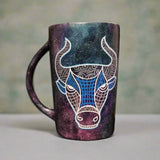 A hand-painted black galaxy mug with Taurus sign