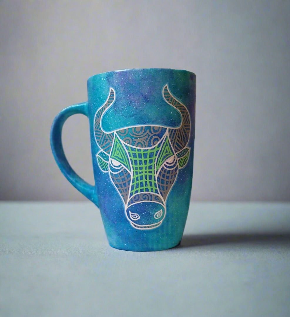 A hand-painted blue galaxy mug with Taurus sign