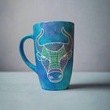 A hand-painted blue galaxy mug with Taurus sign