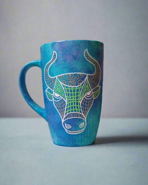 A hand-painted blue galaxy mug with Taurus sign