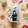 An Ivory hand painted mug with a gothic girl drawn in the center and a web behind her with bats all over the mug